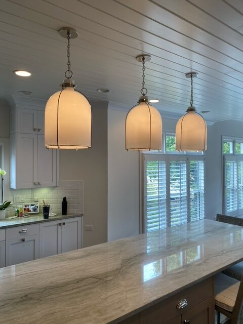 Three lights hanging from a ceiling in a kitchen.