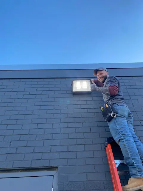 A man on the side of a building with a light.